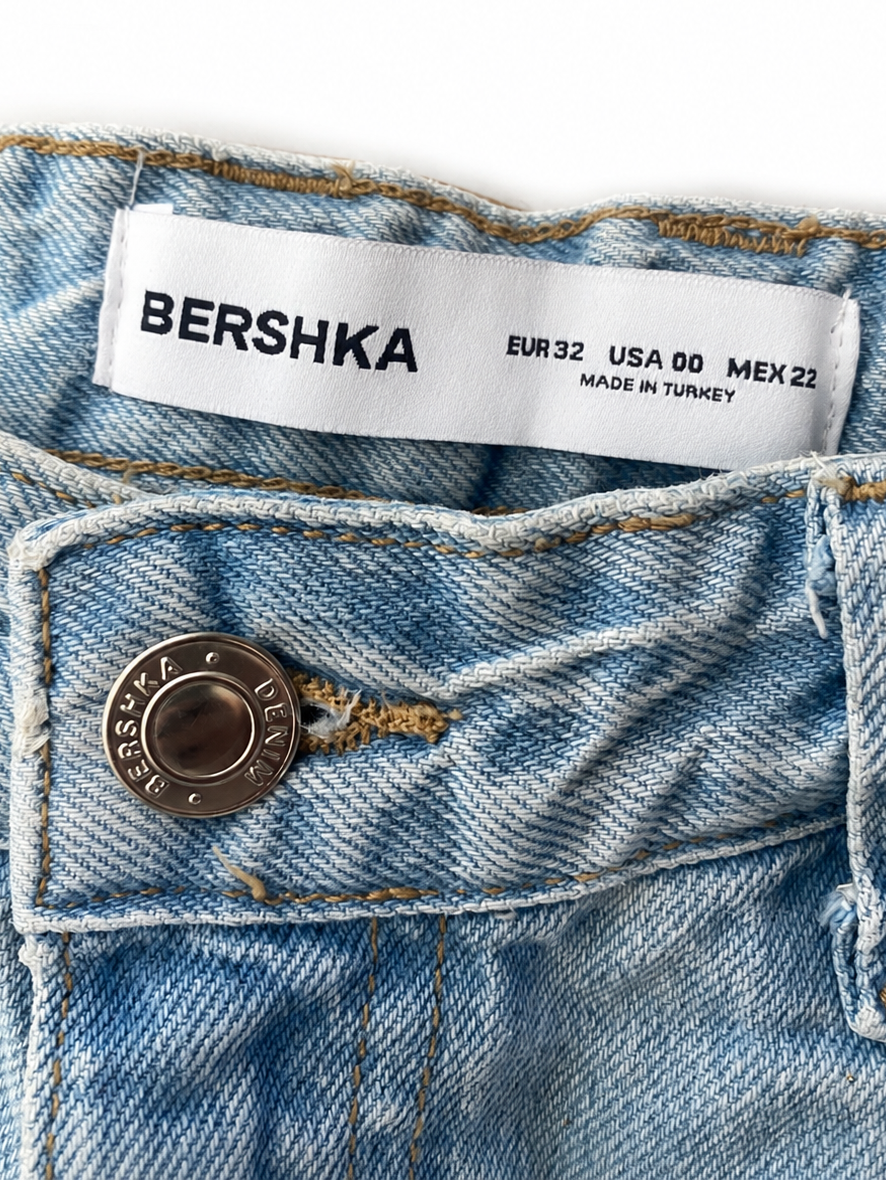 Detailaufnahme der Bershka Jeans mit Markenknopf und Größenetikett EU 32