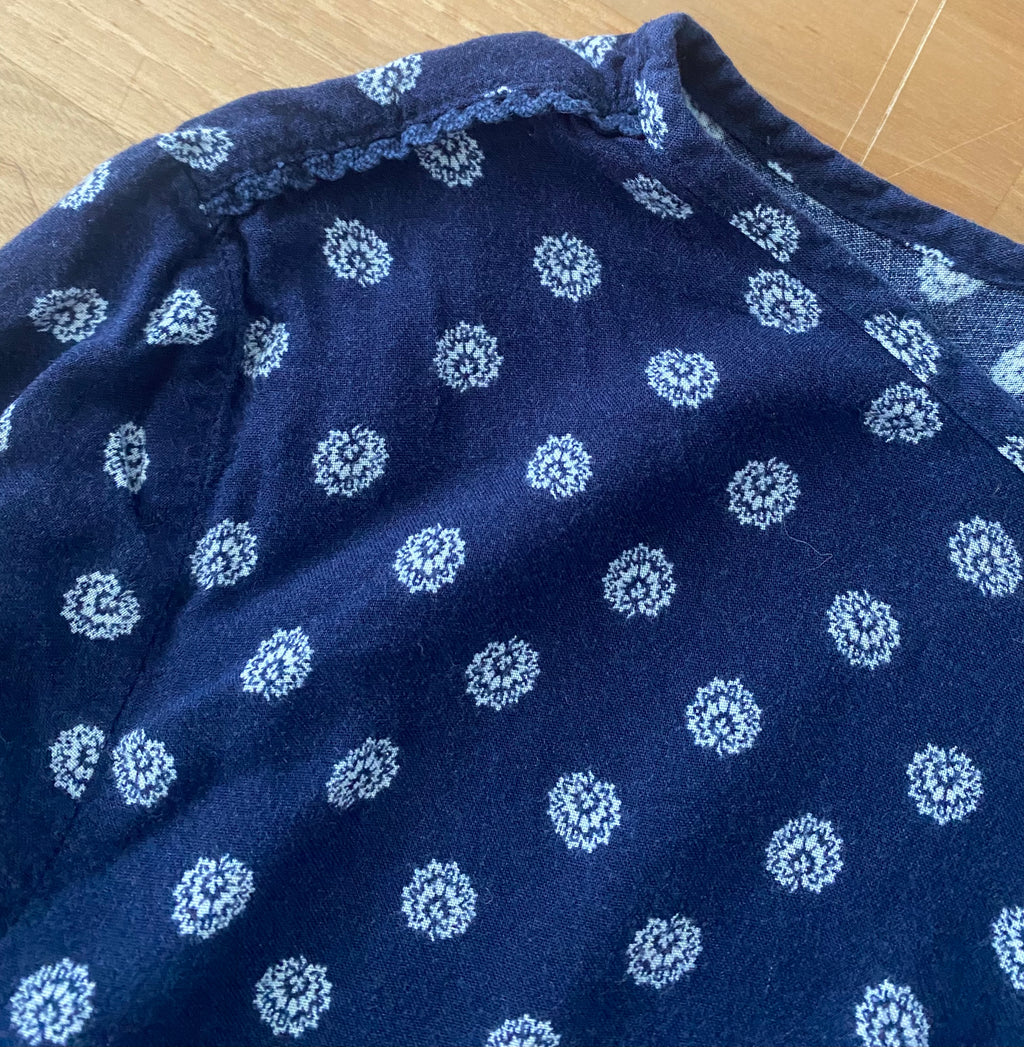 Detailaufnahme des dunkelblauen Langarm-Blusenshirts mit kleinem weißen Allover-Muster und weichem Stoff.