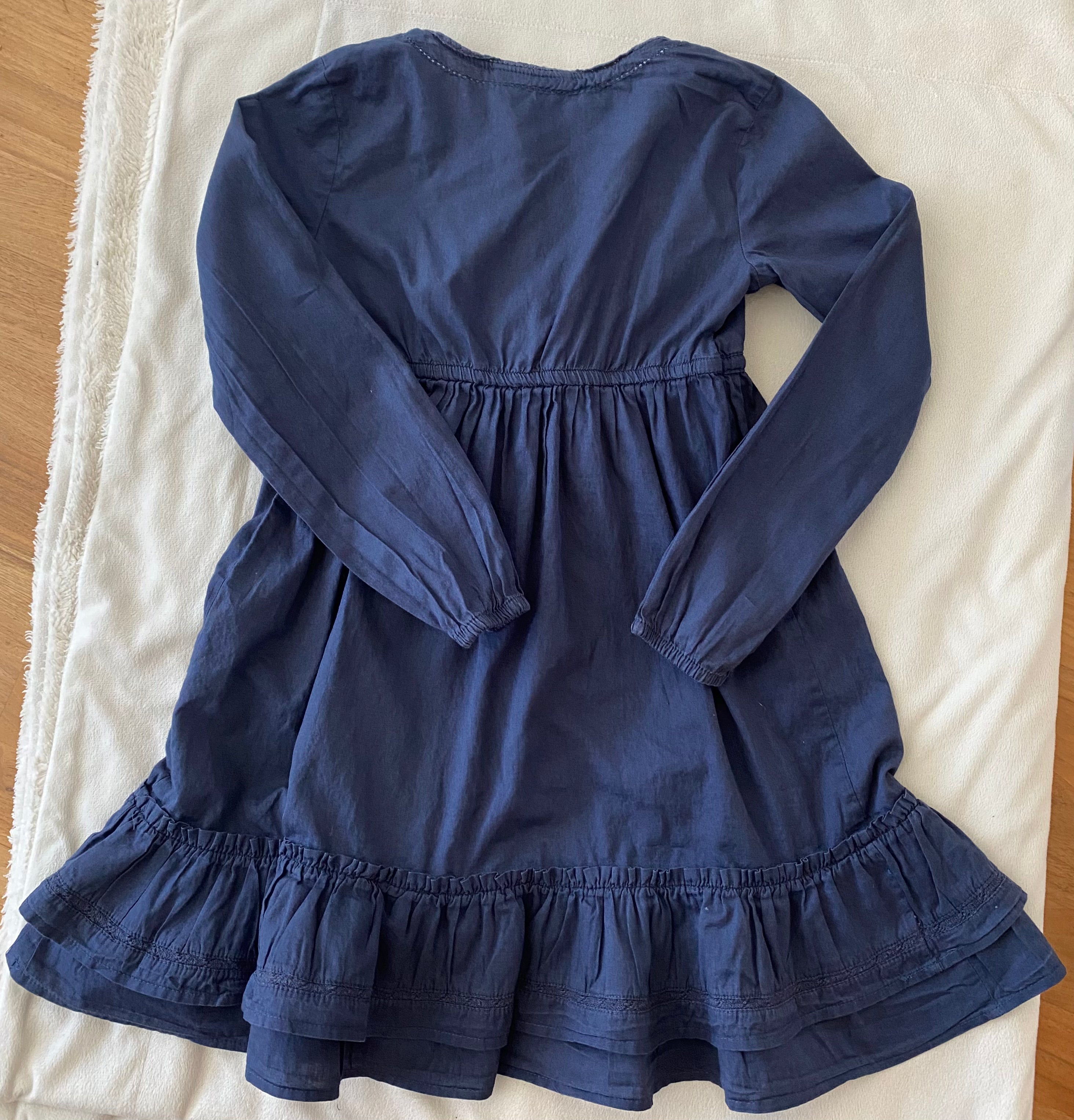 Rückansicht eines blauen H&M Mädchen Kleids Größe 134 mit langen Ärmeln und Rüschen am Saum