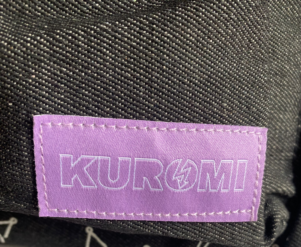 Detailaufnahme des lilafarbenen KUROMI Labels am schwarzen Rucksack