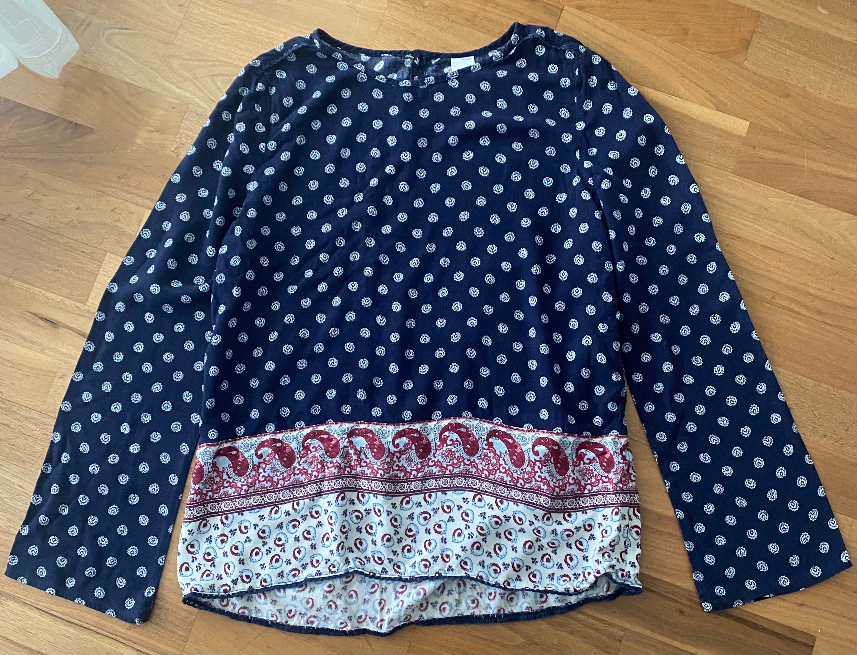 Locker sitzendes dunkelblaues Blusenshirt in Größe 170/176 mit weißem Muster und rot-weißer Paisley-Bordüre vorne.