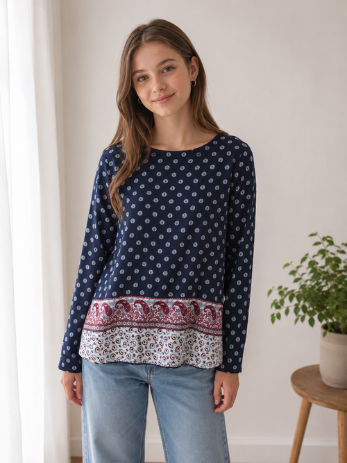 Jugendliche trägt ein locker sitzendes dunkelblaues Langarm-Blusenshirt mit Boho-Muster und Paisley-Bordüre zu Jeans.