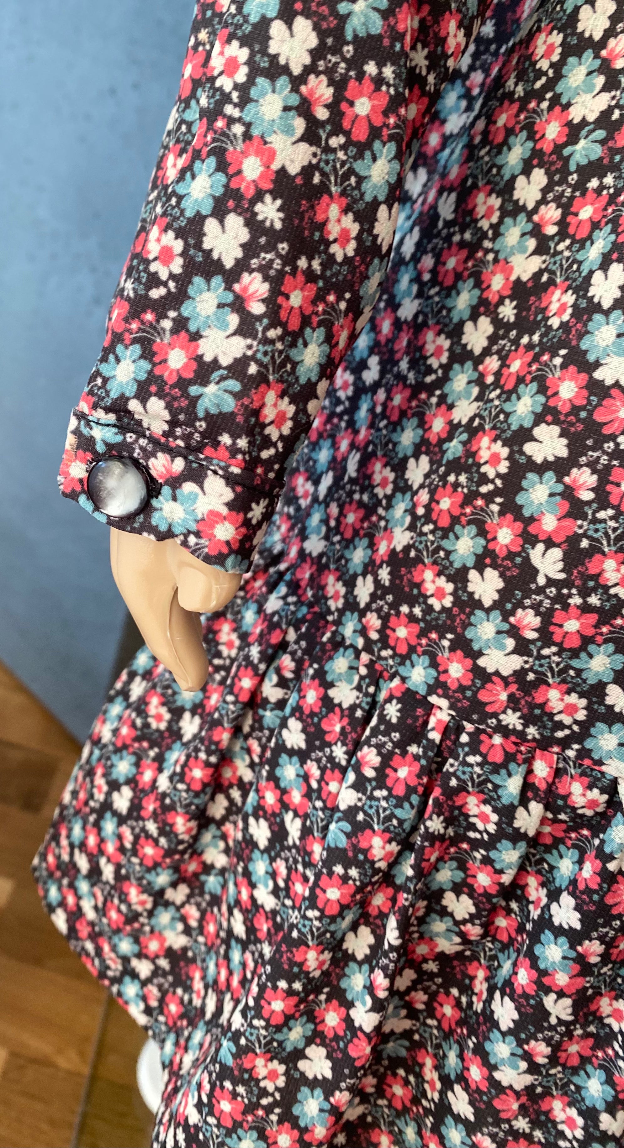 Heidi Detail eines langen Ärmels mit Knopfverschluss bei einem floral gemusterten Mädchenkleid