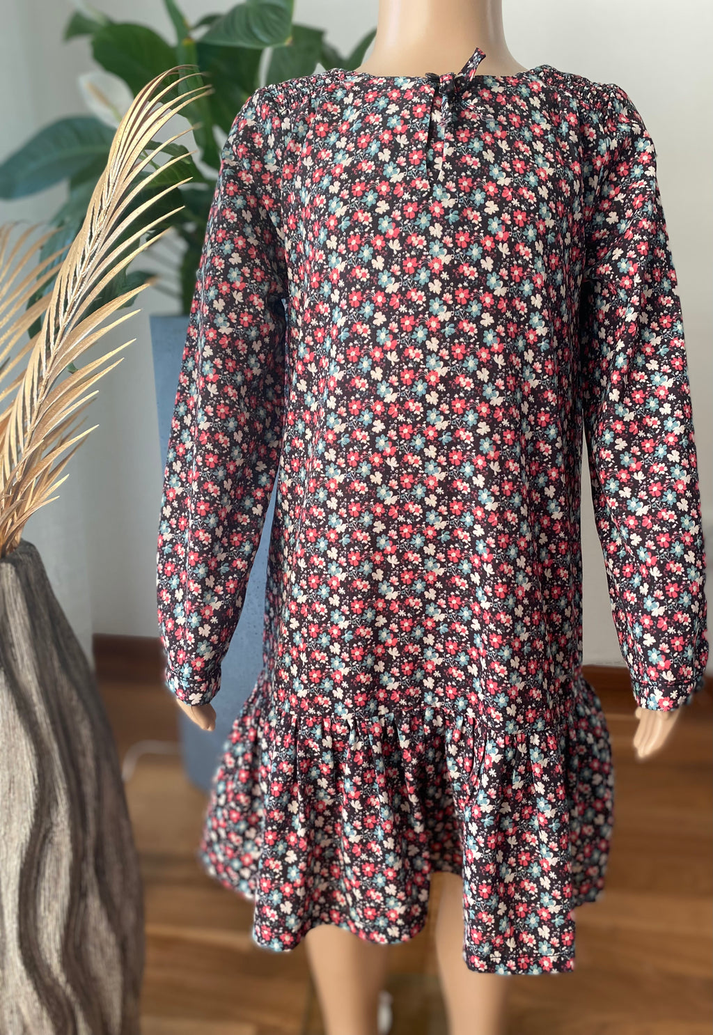 Heidi Langärmeliges Mädchenkleid mit floralem Muster auf einer Puppe von vorne präsentiert