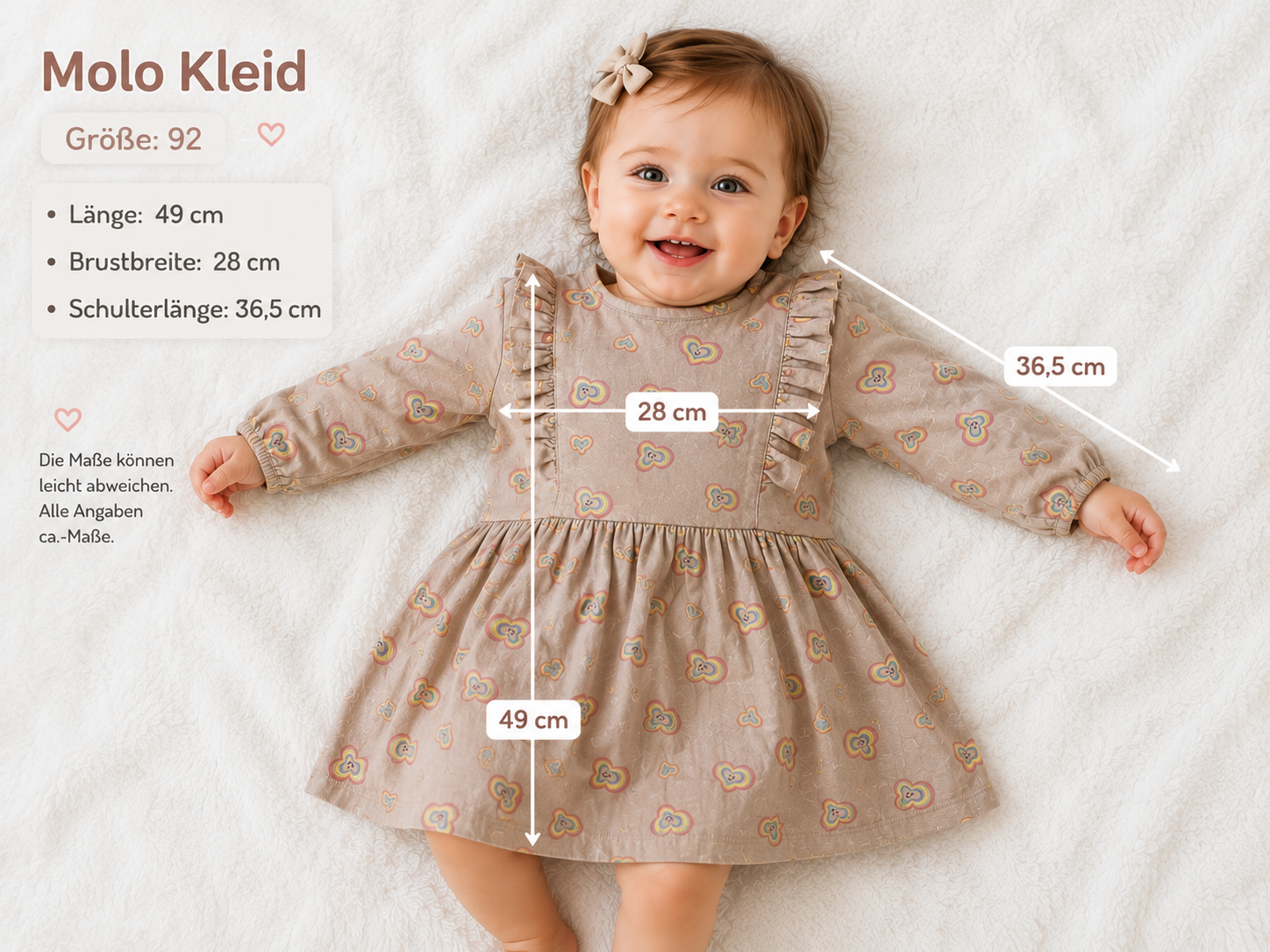 Baby trägt Molo Langarmkleid in Beige mit buntem Herzmuster und Rüschen in Größe 92.