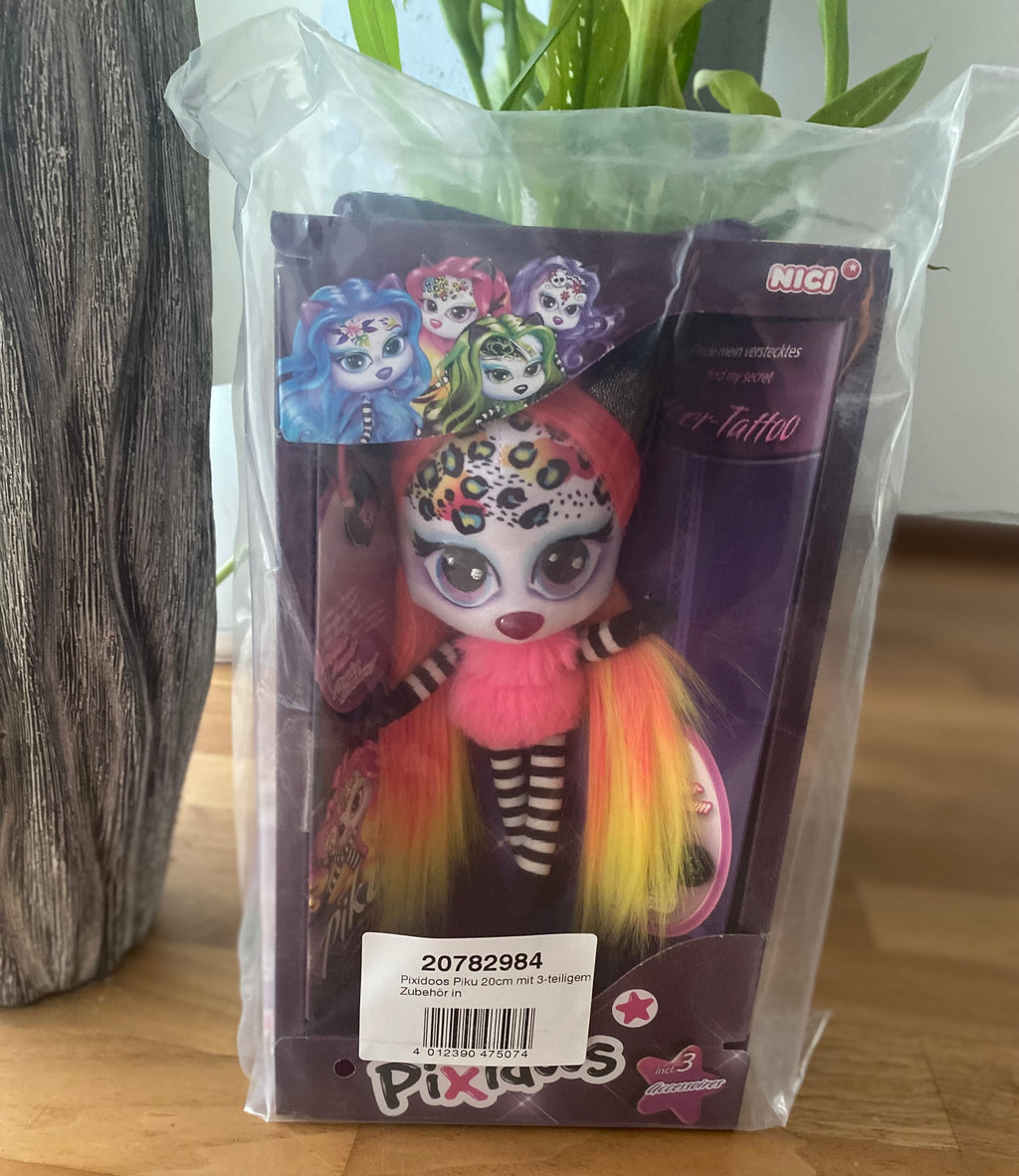 NICI Pixidoos Piku Plüschtier in Originalverpackung auf weißem Hintergrund. Bunte Sammelfigur mit großen Augen, neonfarbenen Haaren und 3-teiligem Zubehörset. Ideal für Kinder und Sammler. Vorderseite