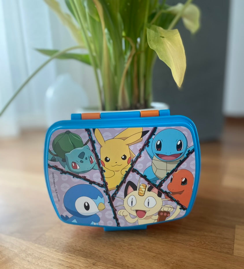 Pokémon Snackbox mit Pikachu, Schiggy, Glumanda, Bisasam, Mauzi und Plinfa auf Holztisch fotografiert