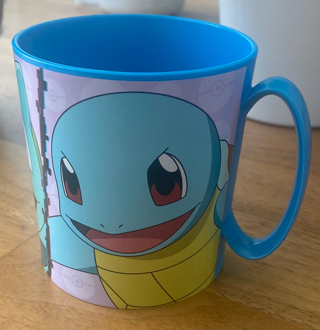 Blauer Pokémon Kinderbecher mit Schiggy Motiv und Henkel auf Holzuntergrund.