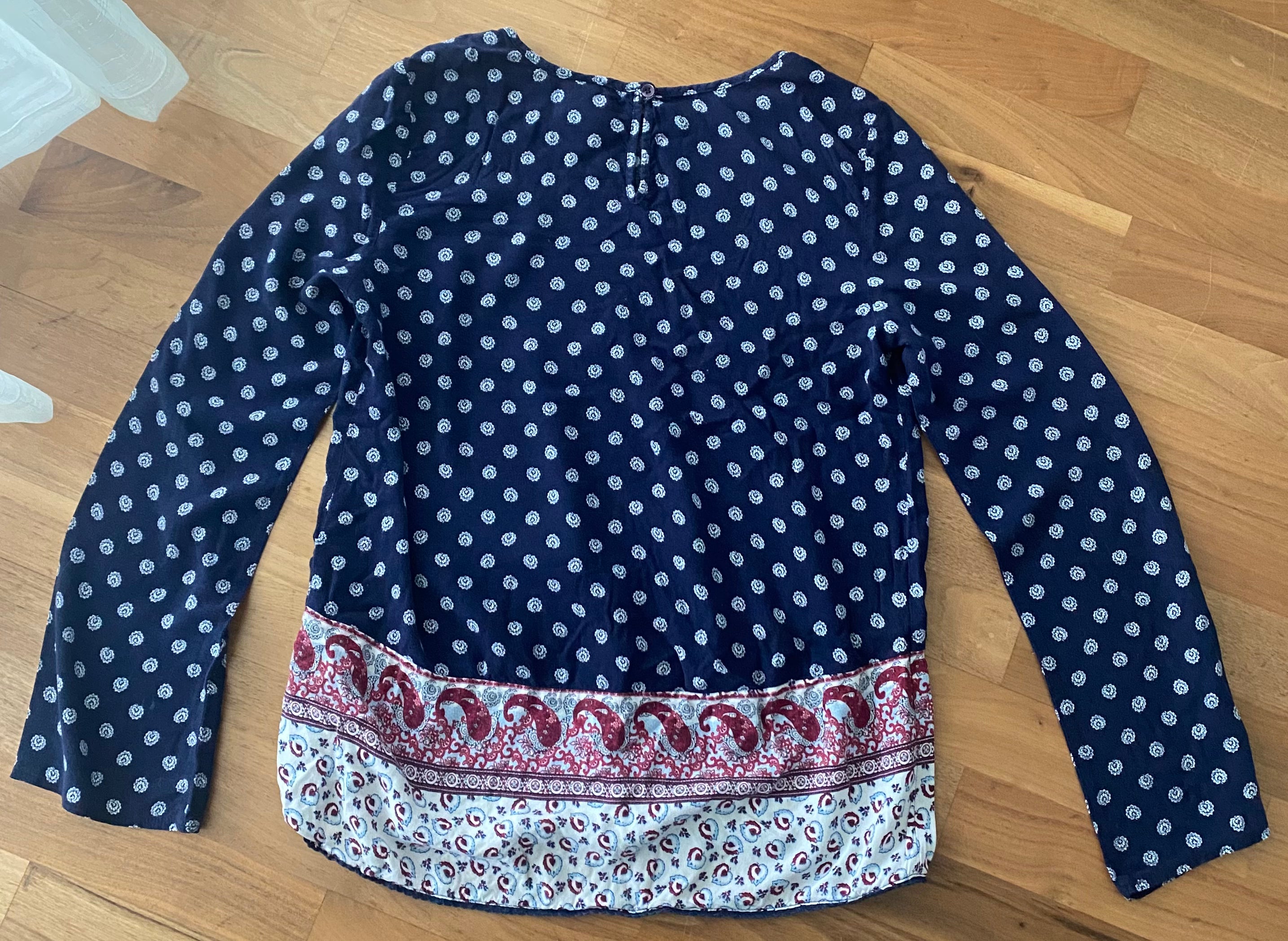 Rückseite eines dunkelblauen Langarmshirts mit feinem weißen Muster und dekorativer Bordüre am Saum.