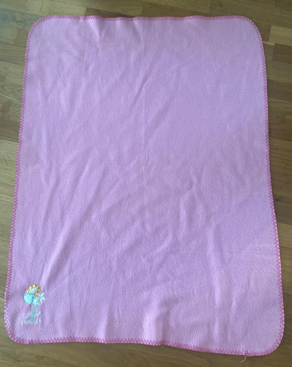 Rosa Babydecke aus weichem Fleece mit dekorativer Blumenstickerei in der Ecke. Kuschelige Kinderdecke mit eingefasstem Rand, ideal für Kinderwagen, Bettchen oder gemütliche Kuschelstunden. Rückseite