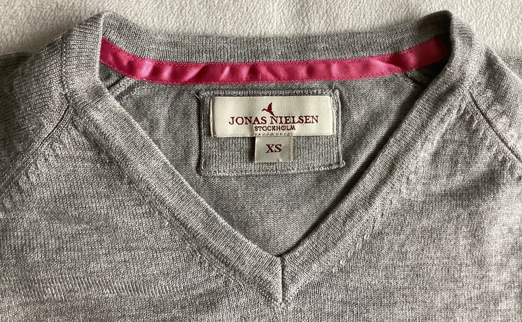 Detailaufnahme V-Ausschnitt Pullover Jonas Nielsen Stockholm XS mit pinkem Nackenband und Markenlabel
