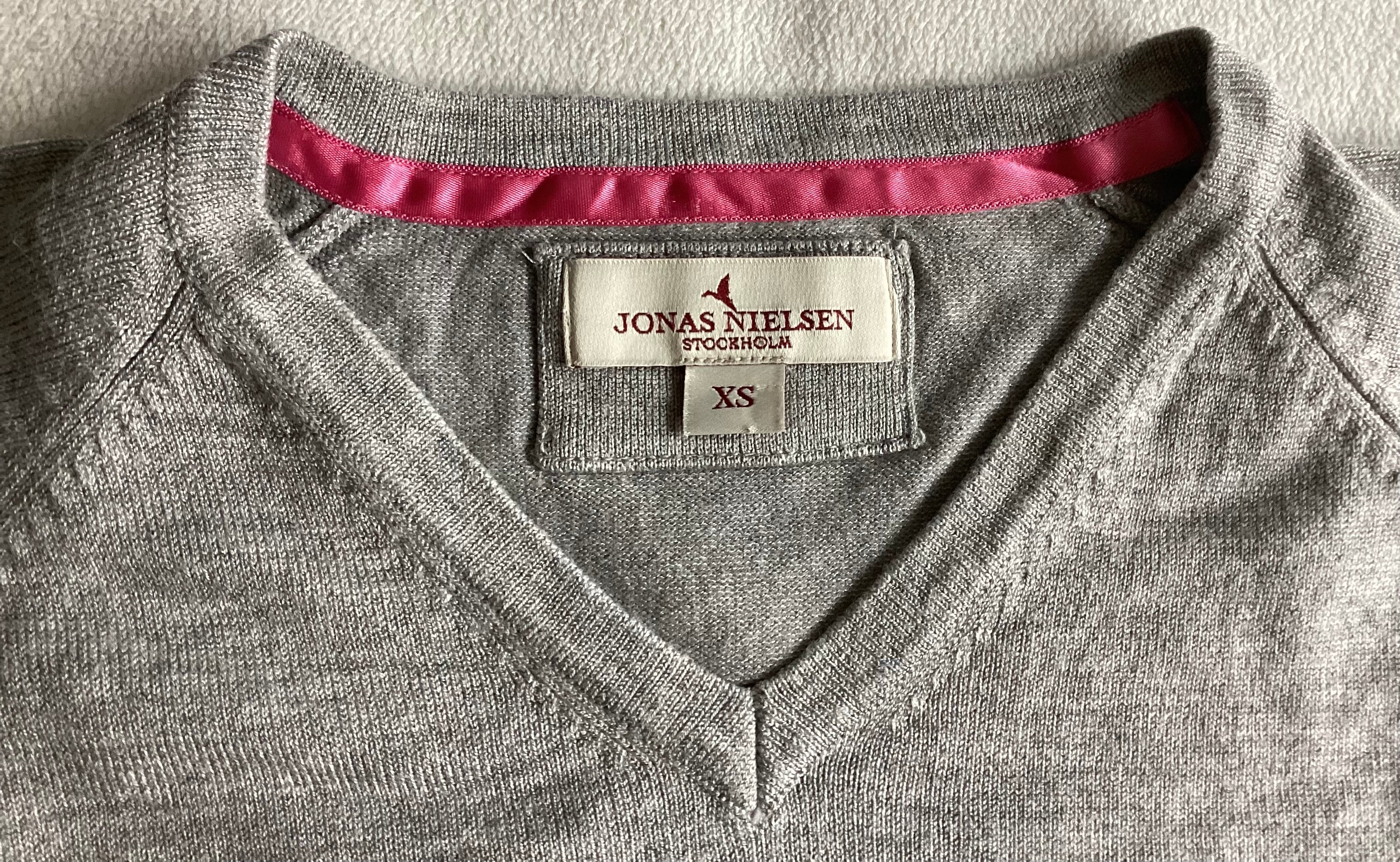 Detailaufnahme V-Ausschnitt Pullover Jonas Nielsen Stockholm XS mit pinkem Nackenband und Markenlabel